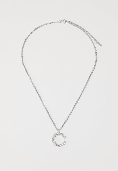 Ασημένια αλυσίδα κολιέ με κυκλικό μενταγιόν διακοσμημένο με μικρούς, διαυγείς κρυστάλλους, που ανακλά το φως με υφή.