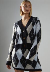 Argyle cardigan i marineblå, lys grå og himmelblå; fluffy tekstur, knaplukning, cropped pasform og brede ærmer.