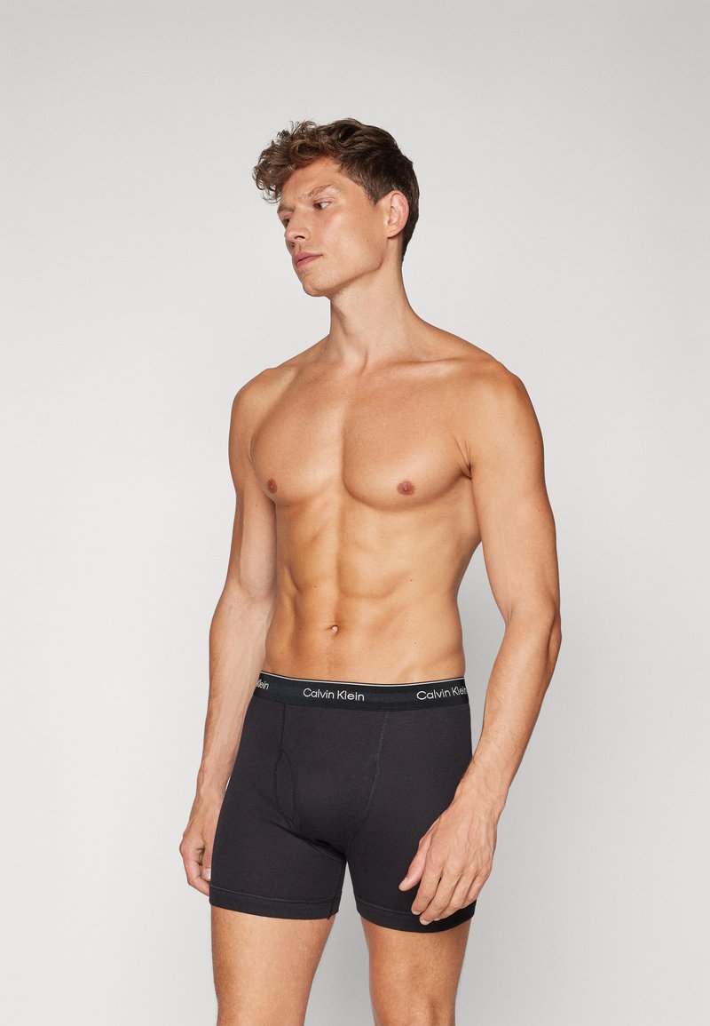 Crne pamučne bokserice s potpisom Calvin Klein na struku, koje imaju uski dizajn i oblikovanu vrećicu za podršku.