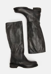 Bottes montantes en cuir noir avec un bout arrondi, une finition texturée et un talon bas empilé. Surface lisse et détails de couture subtils.