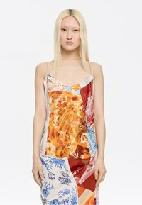 Multikleurige jurk met bloem- en abstracte patronen, met dunne bandjes, een losse pasvorm en een mix van oranje, blauw en roomkleurige tinten.