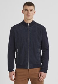 Marineblaue Bomberjacke mit einer glatten Wildlederfront, geripptem Strickkragen und -bündchen, zwei seitlichen Reißverschlüssen und einem taillierten Saum.