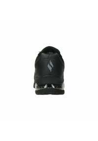Scarpa sportiva nera con un design elegante, materiale sintetico liscio e una suola ammortizzata traslucida con una parte inferiore decorata.