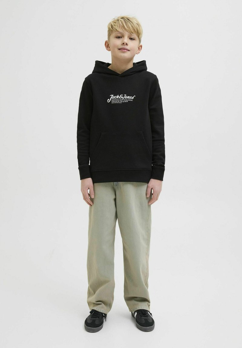 Felpa nera con branding bianco, tasca a marsupio, maniche lunghe, abbinata a pantaloni verde pallido e scarpe da ginnastica nere. Design semplice e informale.