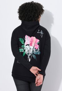 Zwarte hoodie met een grote grafische afbeelding op de achterkant met een schedel en roze rozen. Het materiaal lijkt zacht; het ontwerp bevat groene bladeren en tekstaccenten.