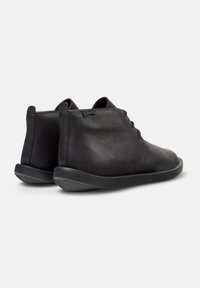Bottes noires en cuir jusqu'à la cheville avec une texture lisse, un design minimaliste, un bout rond et une semelle en caoutchouc avec un motif de traction subtil.