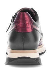 Zwarte leren sneaker met een getextureerde bordeauxrode accent bij de hiel, voorzien van een lichtgekleurde zool en zwarte rubberen grip. Ritsdetail inbegrepen.