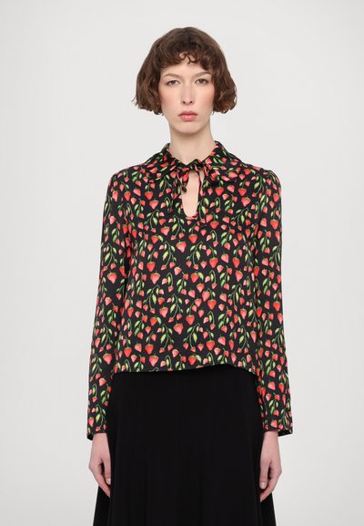 Blouse à manches longues en tissu noir avec un motif floral comportant des cœurs rouges et des feuilles vertes. Encolure en trou de serrure avec un détail nœud.