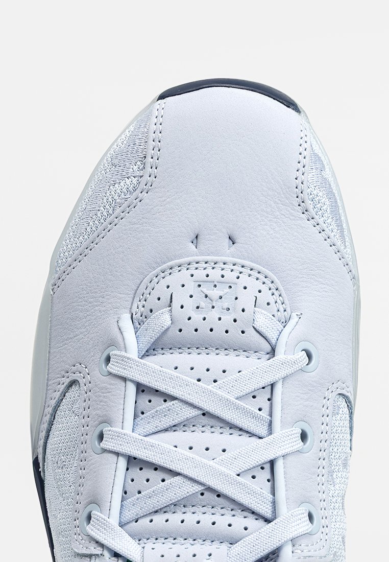 Botte de sport gris clair avec un empiècement en cuir lisse, des panneaux en maille respirante, un bout rond et des lacets en textile. Perforations pour la ventilation.