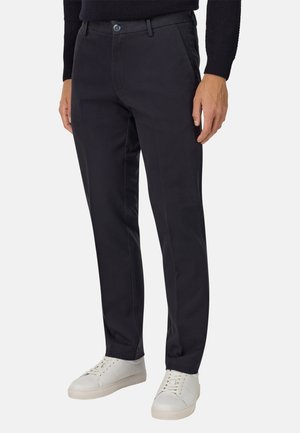 Marineblauwe chinos van katoen met een gladde textuur, voorzien van een knoopsluiting, zijzakken en een getailleerde pasvorm, gecombineerd met witte sneakers.