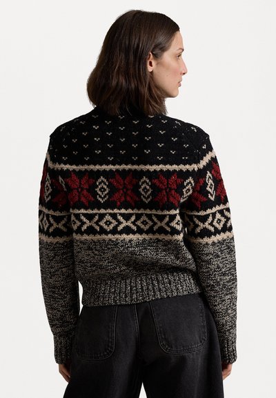 Pulover tricotat cu modele negre, roșii și crem, inclusiv fulgi de zăpadă și designuri geometrice. Material texturat cu un tiv elastic.