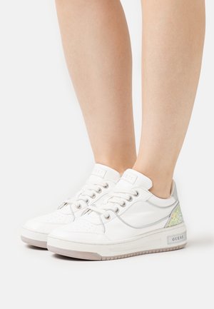 Vita syntetiska sneakers med silverdetaljer, som har perforerat mönster, snörning och en texturerad iridiserande patch på hälkappan.