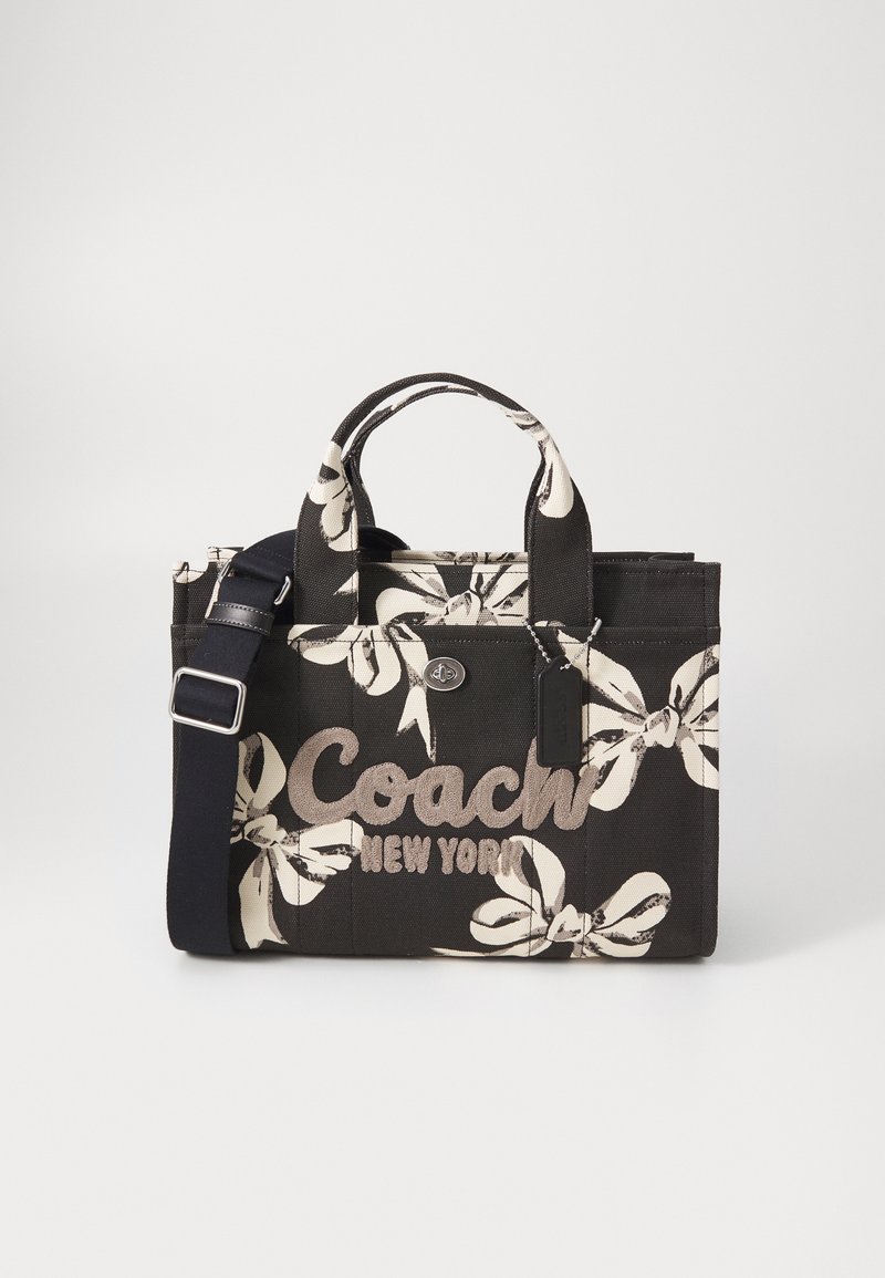 Fekete vászontáska fehér virágmintával, dombornyomott "Coach New York" logóval, rövid fogantyúkkal és állítható vállpánttal.
