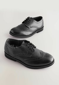 Čierne kožené brogues so perforovanými detailmi, okrúhlou špičkou a šnurovaním. Má nízky opätok a hladký povrch.
