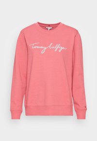 Felpa rosa realizzata in morbido cotone, con maniche lunghe, collo rotondo e testo bianco "Tommy Hilfiger" sulla parte anteriore.