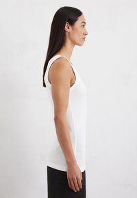 Witte tanktop met een slim fit, brede schouderbanden en een gladde textuur. Heeft een ronde hals en zijnaad voor een gedefinieerde vorm.