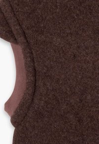 Gilet en feutre marron avec une texture lisse et douce, et des accents en coton rose clair contrastants le long des bords et des emmanchures.
