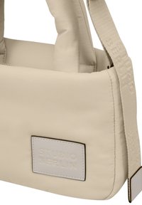Beige Stoffhandtasche mit gepolsterter Struktur, kurzen Griffen und einem langen Schultergurt. Verfügt über das eingeprägte "STUDIO BERLIN"-Logo auf einem Leder-Patch.