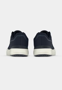 Ζεύγος αθλητικών παπουτσιών σε σκούρο μπλε χρώμα με λευκές σόλες, εμφανιζόμενα από την πίσω πλευρά σε απλό λευκό φόντο.