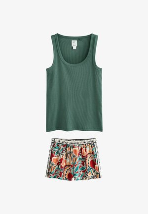 Zelené žebrované tílko bez rukávů v kombinaci s vícebarevnými krátkými kalhotami s tropickým květinovým potiskem a bílým pasem s černým nápisem.