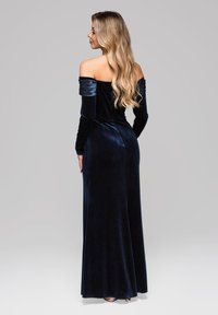 Langes Samtkleid mit schulterfreiem Design in Tiefblau, ausgestattet mit enganliegenden Ärmeln, einer schlanken Silhouette und einer glatten, weichen Textur.