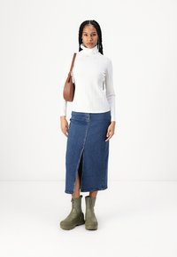 Valge soonikkoes kõrge kaelusega sviiter, sinine denim midi seelik ees lõhiku ja oliivirohelised pahkluu saapad. Pruun õlakott aksessuaarina.
