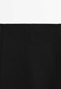 Jupe en tissu stretch noir avec une taille cintrée et des détails de couture verticale, présentant une texture lisse et un design minimaliste.