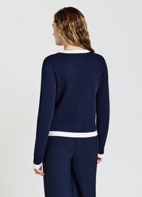 Maglione lavorato a maglia di colore blu navy con rifiniture bianche col colletto e all'orlo, con maniche lunghe e una vestibilità comoda. Texture liscia.