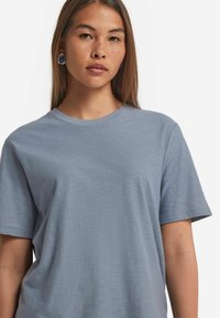 Ljusa blå kortärmad t-shirt i mjukt tyg, med rund halsringning och en avslappnad passform. Subtil textur synlig på tyget.