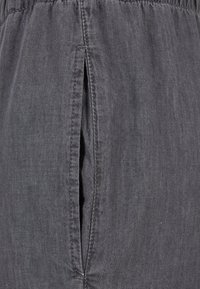 Tissu gris avec une surface légèrement texturée, présentant un détail de fente à l'avant et une taille froncée pour le confort et la facilité de port.