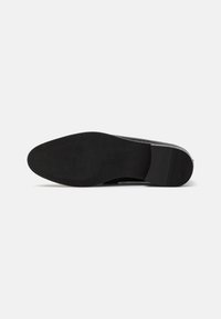 Suela de zapato negra con superficie texturizada, forma de punta redonda y tacón plano. Material de goma suave con sutiles surcos y patrones.
