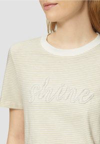 Gestreiftes T-Shirt aus weichem Stoff mit einem cremfarbenen Kragen und dem Wort "shine" in perlenartiger Stickerei.