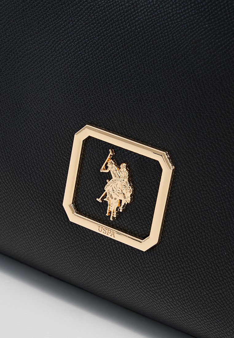 Schwarze strukturierte Handtasche mit einem goldenen rechteckigen Logoemblem, das ein Polo-Spieler-Design und die Aufschrift "USPA" am Boden zeigt.
