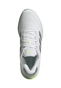 Zapatilla deportiva blanca con parte superior texturizada, acentos grises, tres rayas negras y suela verde. Presenta cordones y un collar acolchado.