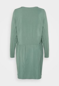 Vestido de mangas compridas em verde suave com decote arredondado. Apresenta uma cintura franzida para uma forma subtil. Textura de tecido suave.