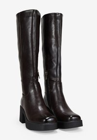 Botas de cuero marrones hasta la rodilla con un tacón ancho, que cuentan con un cierre lateral y una textura suave, destacando un diseño elegante y moderno.