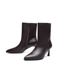 Ciemnobrązowe skórzane kozaki do połowy łydki z ostrymi czubkami, bocznym zamkiem błyskawicznym i smukłymi obcasami, przedstawione na białym tle.