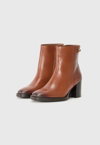 Bottines en cuir marron avec une finition lisse, à bouts ronds, un petit talon carré et un détail à boucle sur le côté.