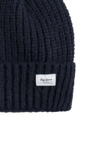 Gorro de punto azul marino hecho de material suave con textura acanalada. Presenta una pequeña etiqueta blanca con la marca "Pepe Jeans London".