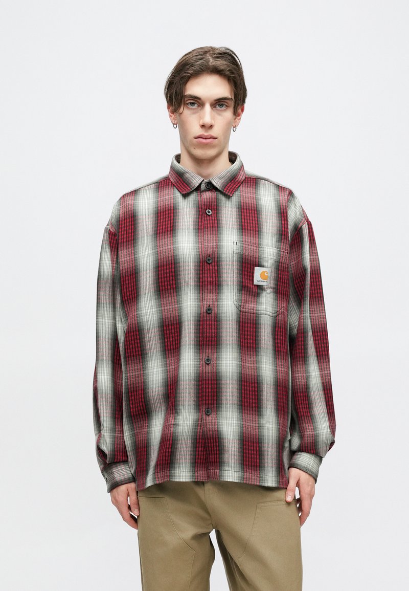Red and gray plaid shirt in a relaxed fit, featuring a button-down collar, long sleeves, and a chest pocket with a logo patch.