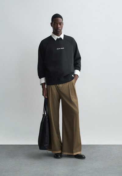 Must musta sweatshirt valge logo ja valge särgiga; laiad beežid püksid; must kott kaasas; sujuvad tekstuurid.