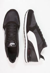 Zapatillas negras y grises con parte superior de textil y ante, detalles de acento en blanco, cordones redondos y suela de goma con un dibujo texturizado.