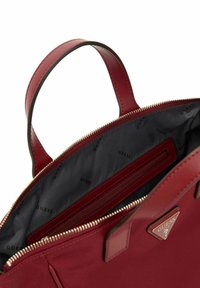 Bolso de mano de cuero rojo con asas dobles, cierre de cremallera y un interior negro que cuenta con un bolsillo con cremallera y un patrón de logo.