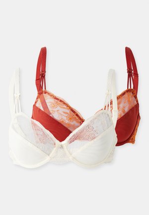 Zwei BHs: einer weiß mit Spitzenbesatz und Blumenmuster, der andere rot mit gemustertem Netz und goldenen Akzenten. Verstellbare Träger in passenden Farben.
