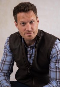 Brown leather vest over a blue and white plaid shirt. The vest has a zip front, while the shirt features button details and long sleeves.