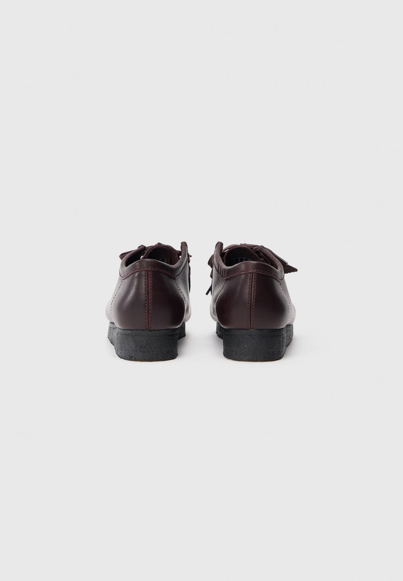 Dark burgundy leather shoes with a low profile, round toe, and textured black rubber sole. Features a contrasting stitch detail.