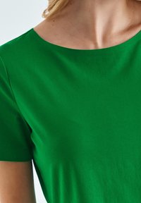 Maglietta verde a maniche corte con scollatura rotonda. Texture liscia e design aderente. Nessun motivo visibile o dettagli hardware.