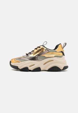 Chunky Sneaker mit einem Obermaterial aus Mesh in Gold und Beige, schwarzer Gummisohle und metallischen Akzenten. Dicke Zwischensohle mit strukturierten Details.