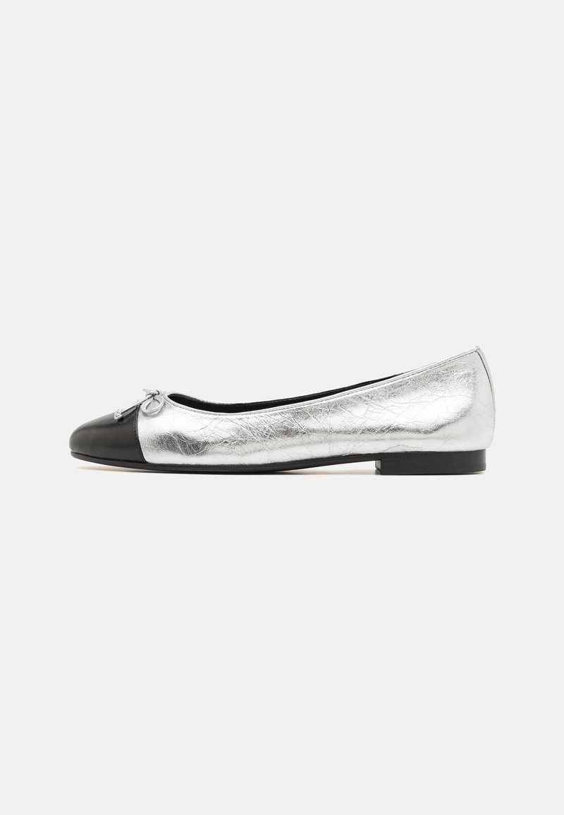 Chaussure plate argentée métallique avec embout noir et petit nœud, talon bas, vue latérale sur fond blanc.