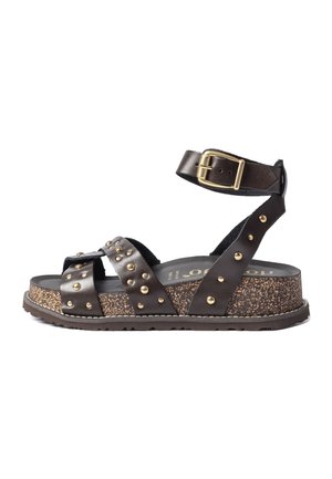 Sandale en cuir marron avec des clous dorés, bride de cheville réglable avec boucle dorée, et semelle épaisse en liège tacheté.